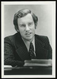 Portrait, pinstripe suit, leaning right elbow on desk
